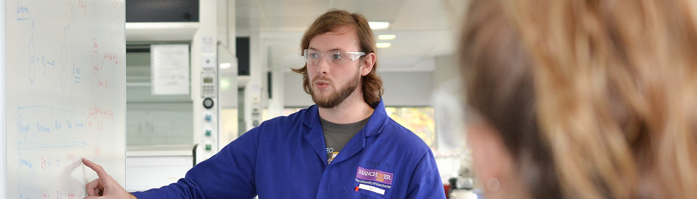 Male student explaining contents of whiteboard to other students